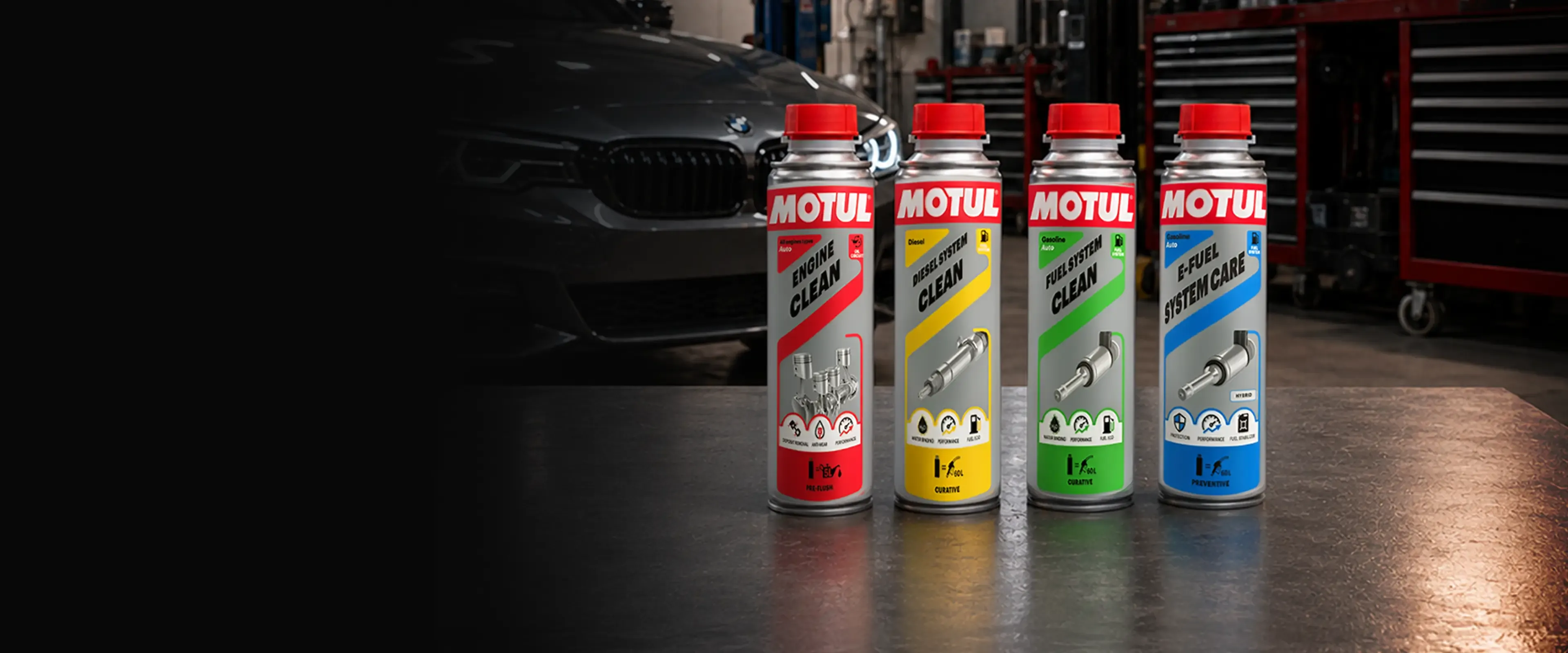 Motul additives range on a workshop bench in front of a car