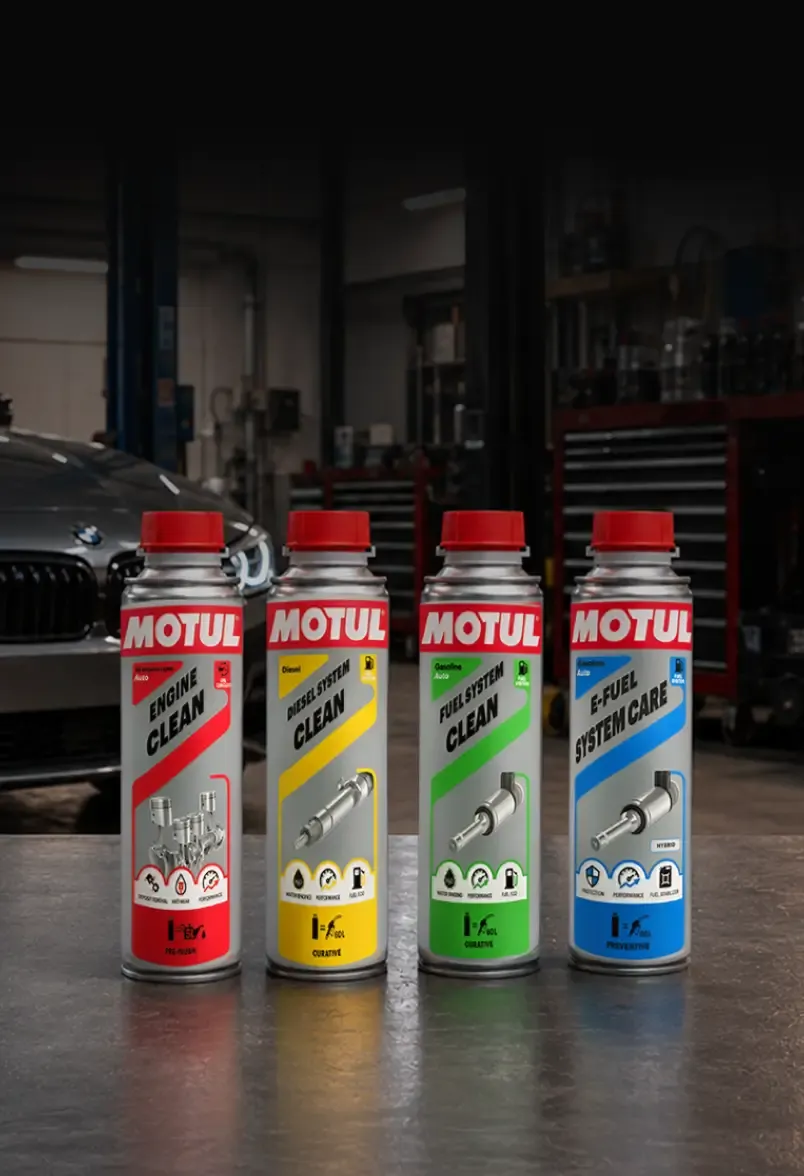 Motul additives range on a workshop bench in front of a car