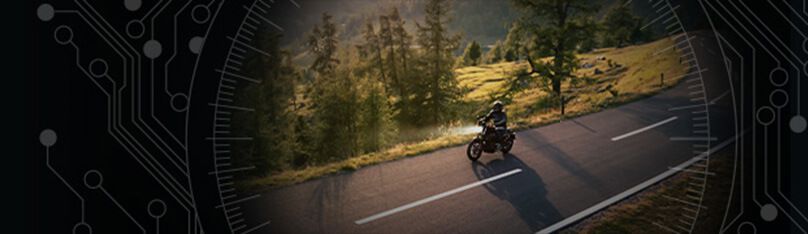 Motocykl jedzie krętą, górską drogą wśród drzew