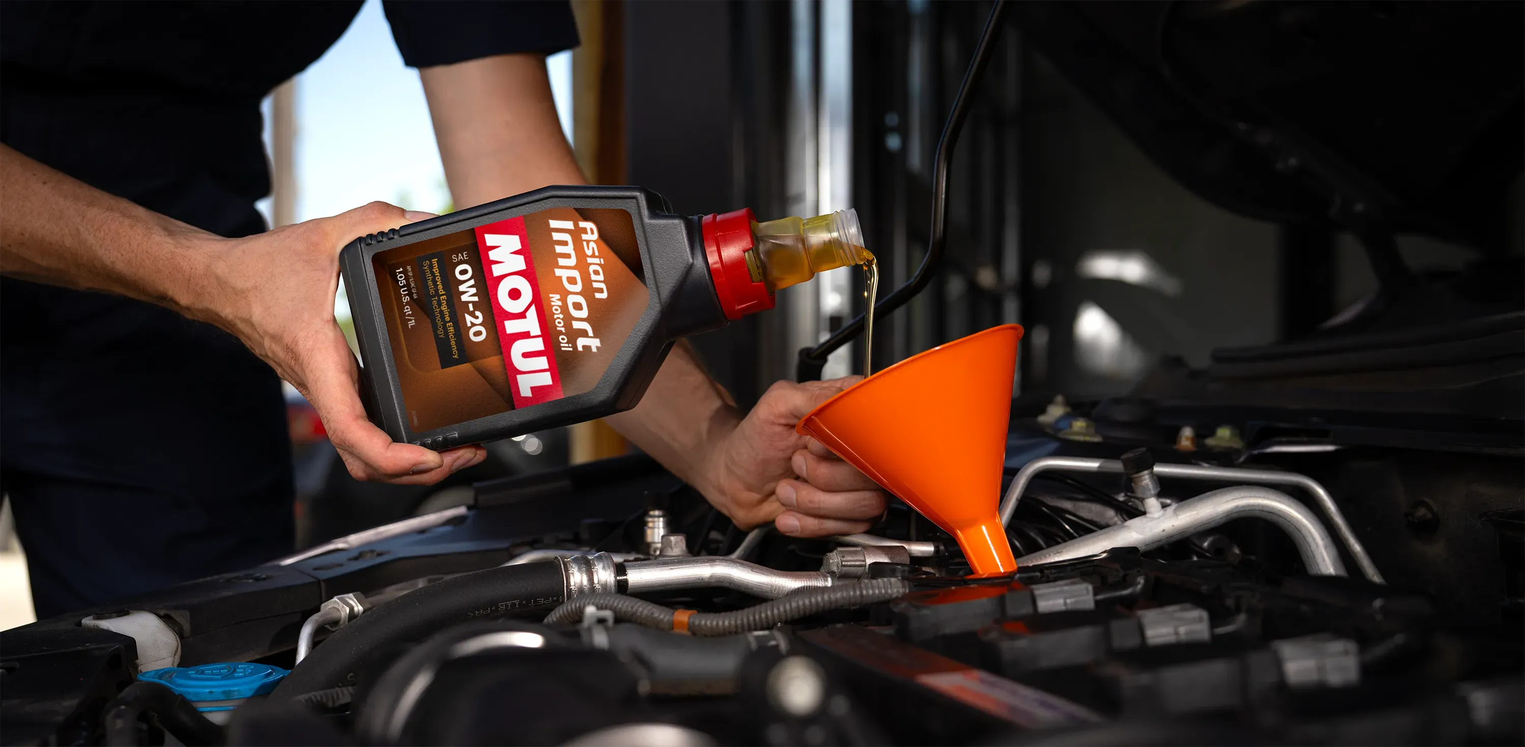 Shop tech pouring Asian Import Motor Oil